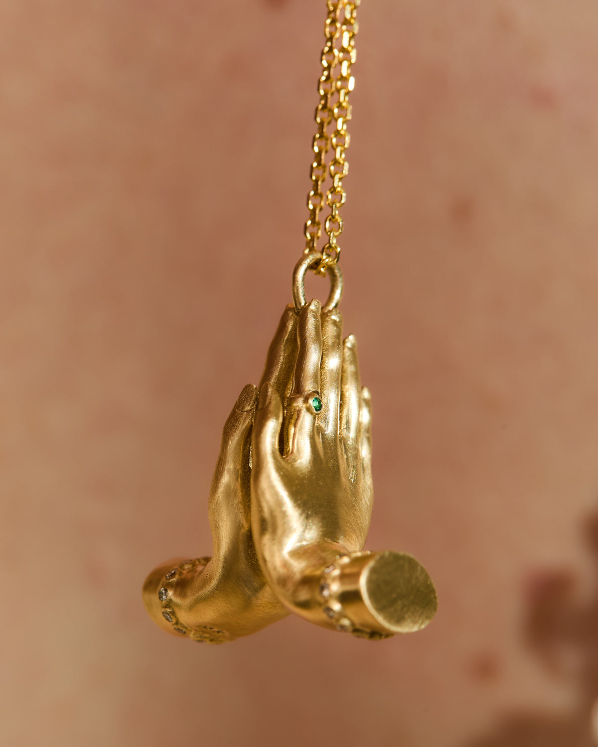 side view 14K gold Namaste necklace featuring sculpted praying hands with natural diamonds, emerald and ruby.