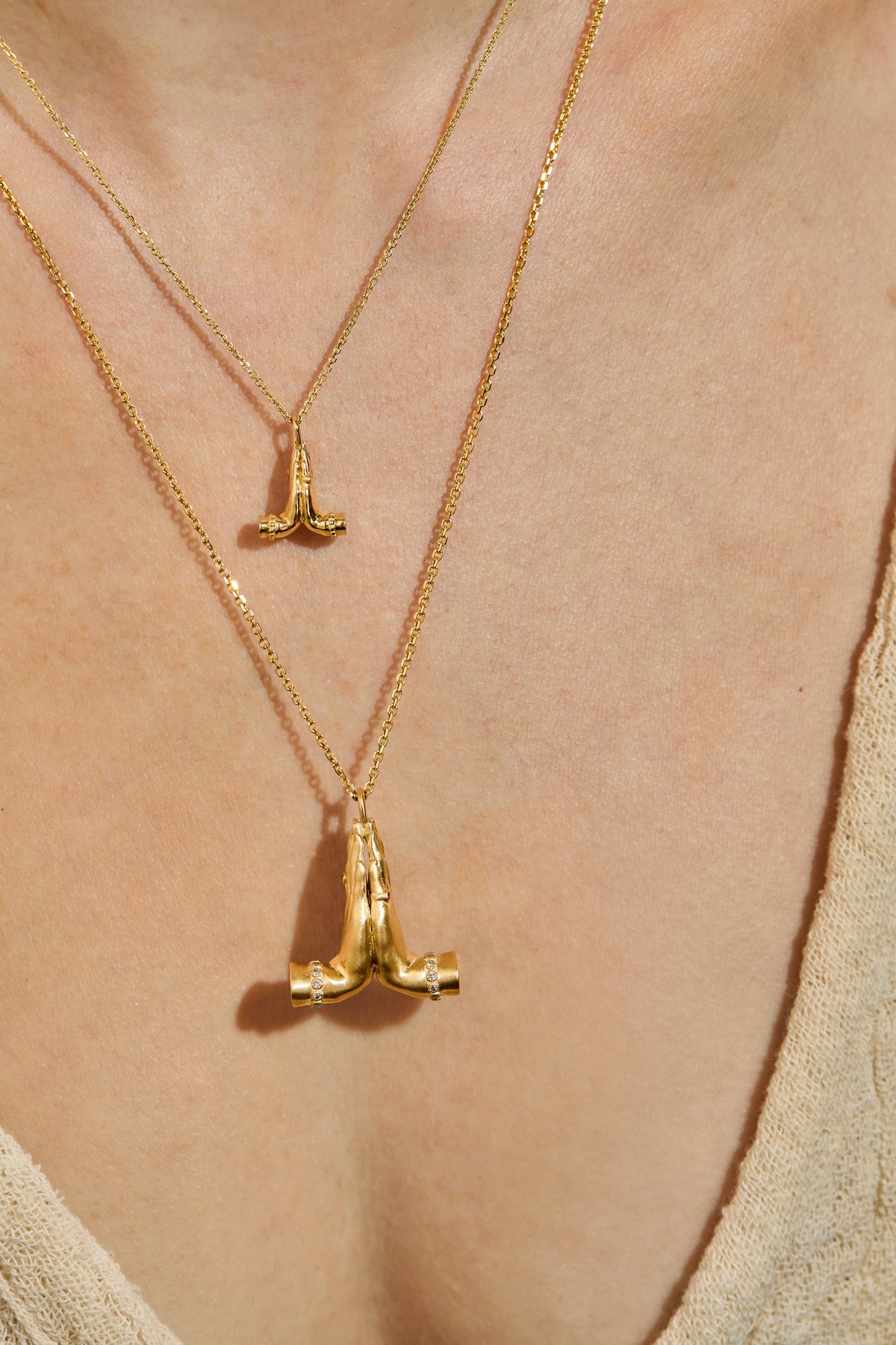14K gold Namaste necklace featuring sculpted praying hands with natural diamonds, emerald and ruby and mini namaste on neck