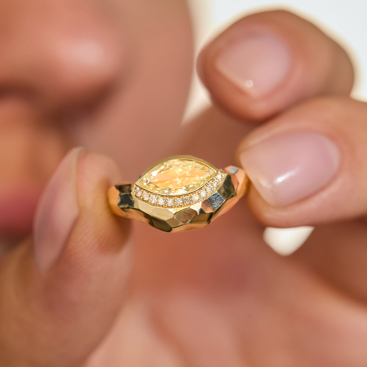  one-of-a-kind fancy yellow marquise diamond curve ring in 14K gold with white diamond pavé and hand-carved gold facets hold between fingers