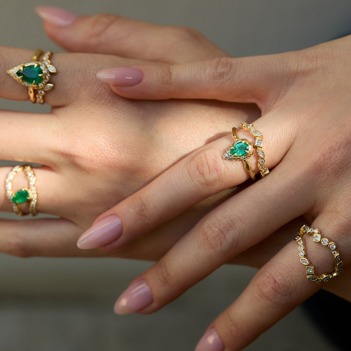 Mystic emerald and diamond ring with a 0.70 ct pear-shaped natural emerald and sculptural 14K yellow gold setting worn on hand with adama diamond rings