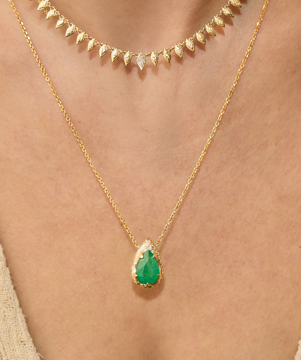 Pear-cut natural emerald drop necklace with hand-carved textured 14K yellow gold setting and delicate gold chain worn on neck