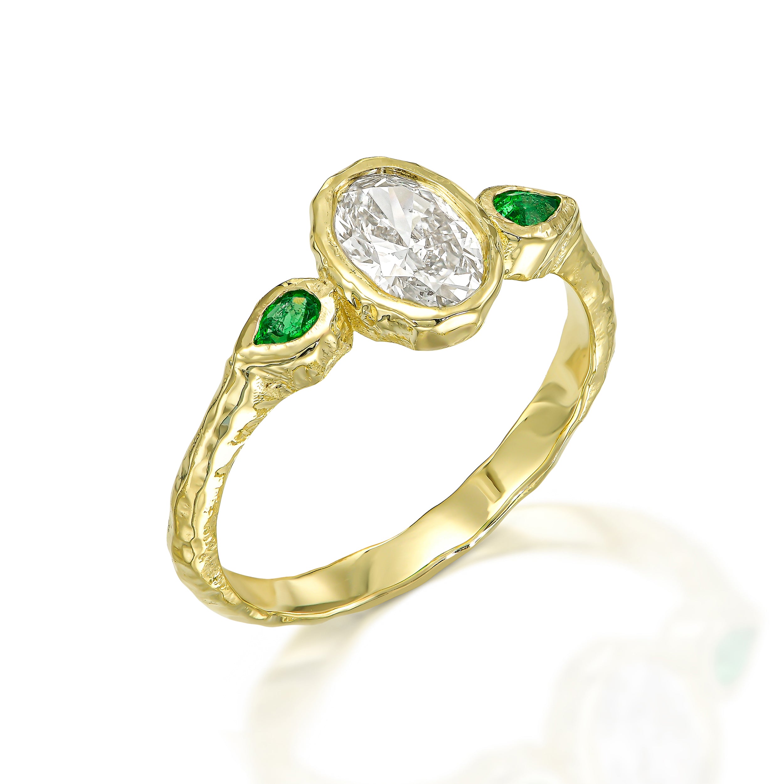 Organic 14K gold engagement ring featuring an oval diamond and two vivid green pear emeralds