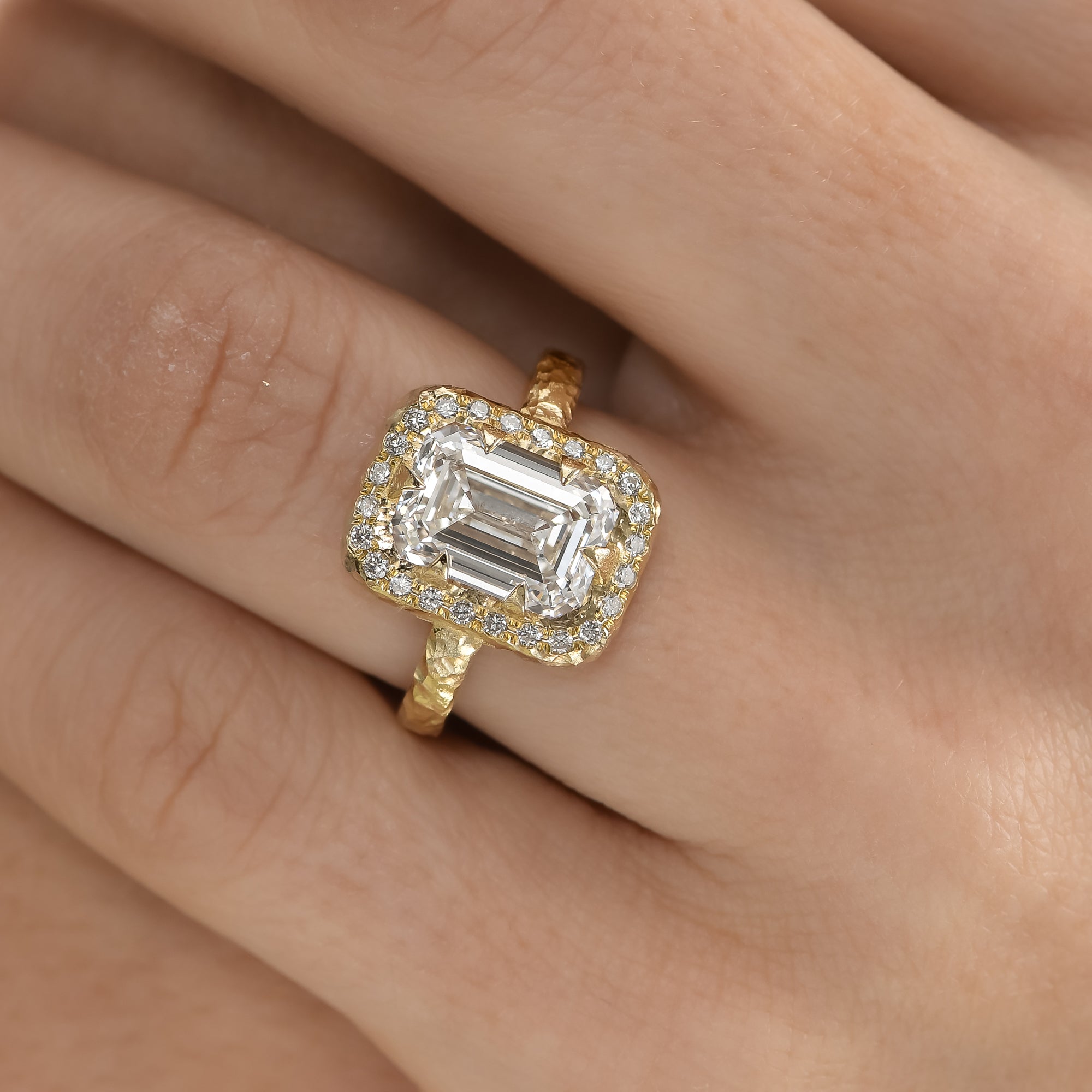 4 ct emerald-cut diamond engagement ring with a natural diamond halo and hand-carved textured 14K yellow gold.