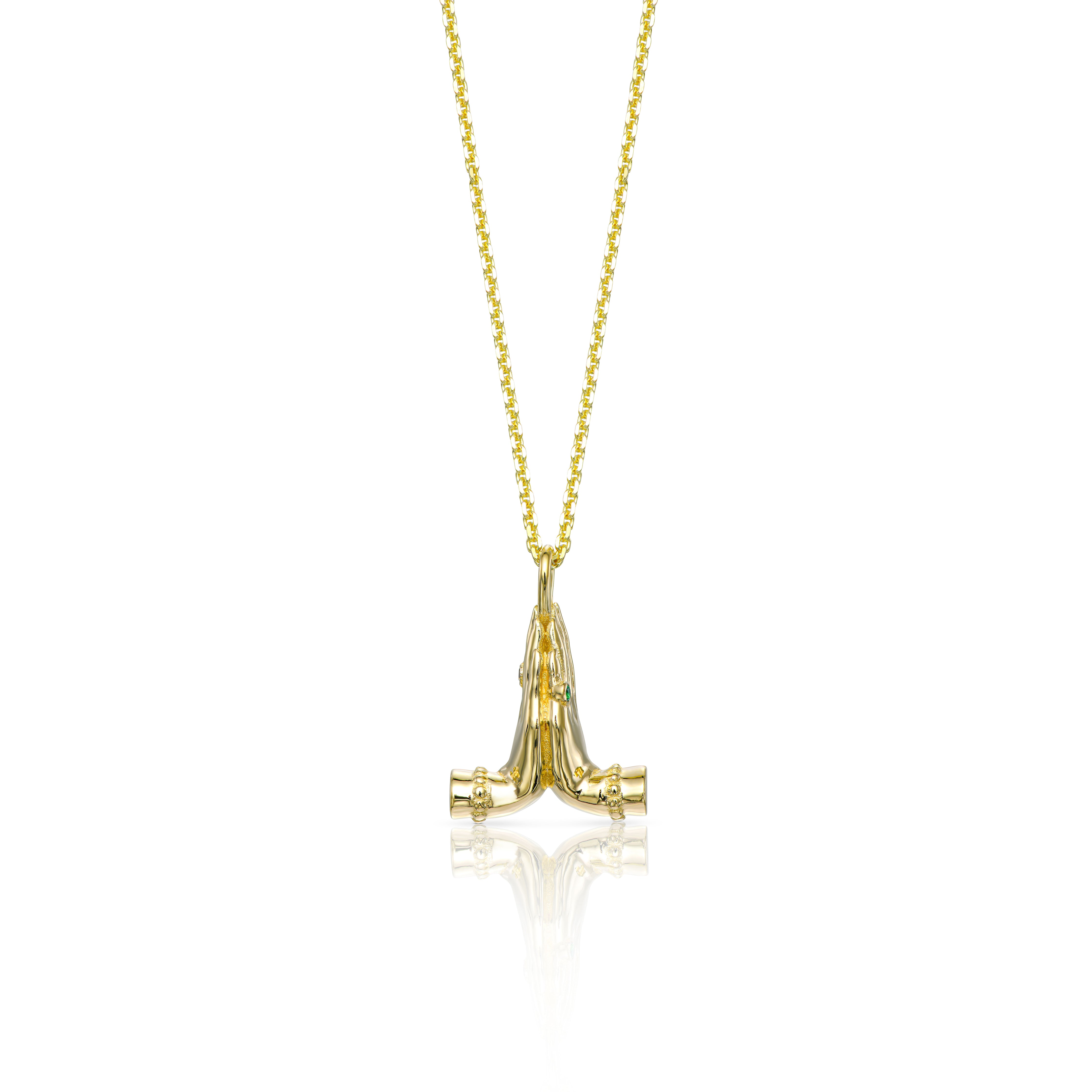 Mini Namaste gold necklace featuring sculpted praying hands with a natural emerald and diamond.