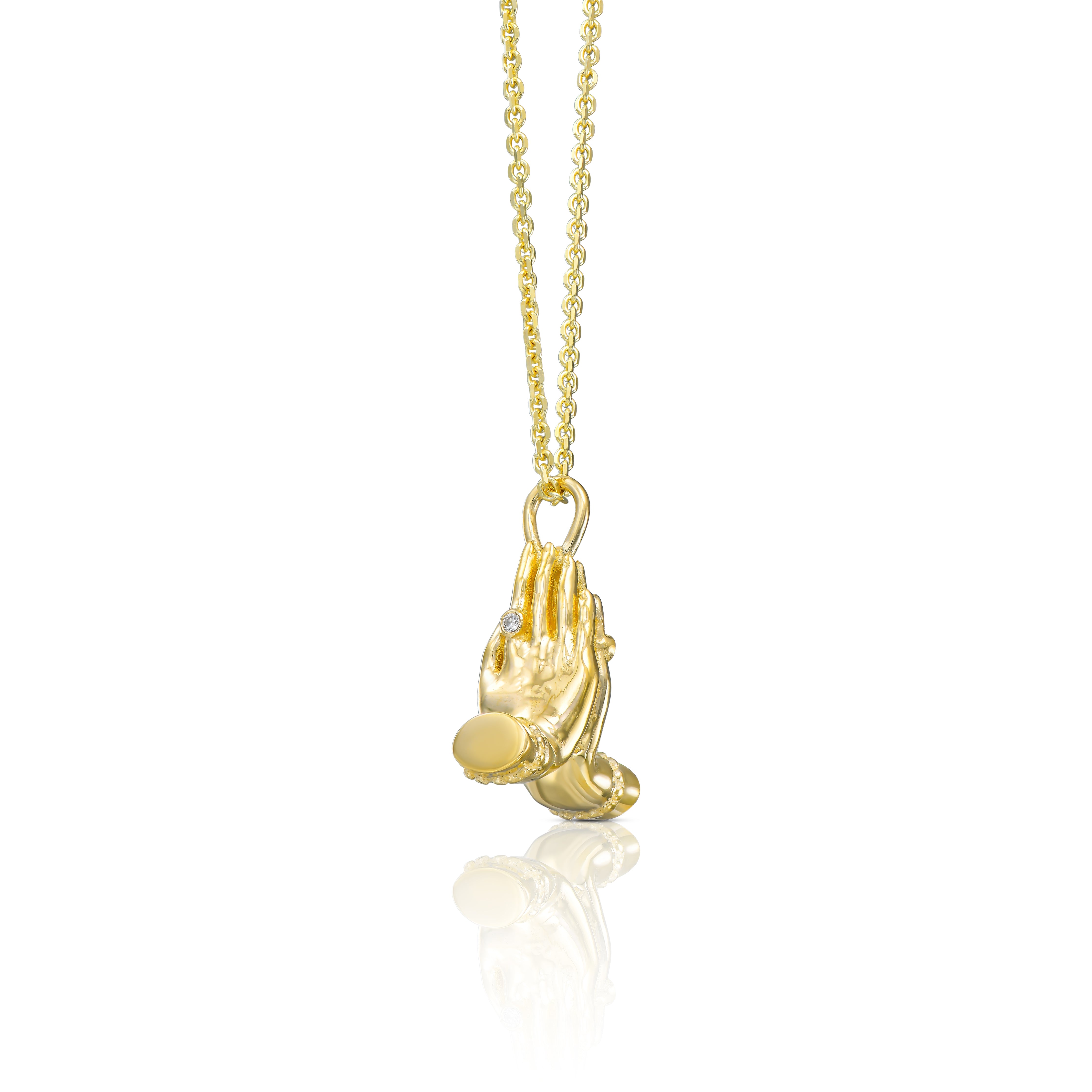 Angled view of a 14K gold Mini Namaste necklace with sculptural praying hands and gemstone accents.