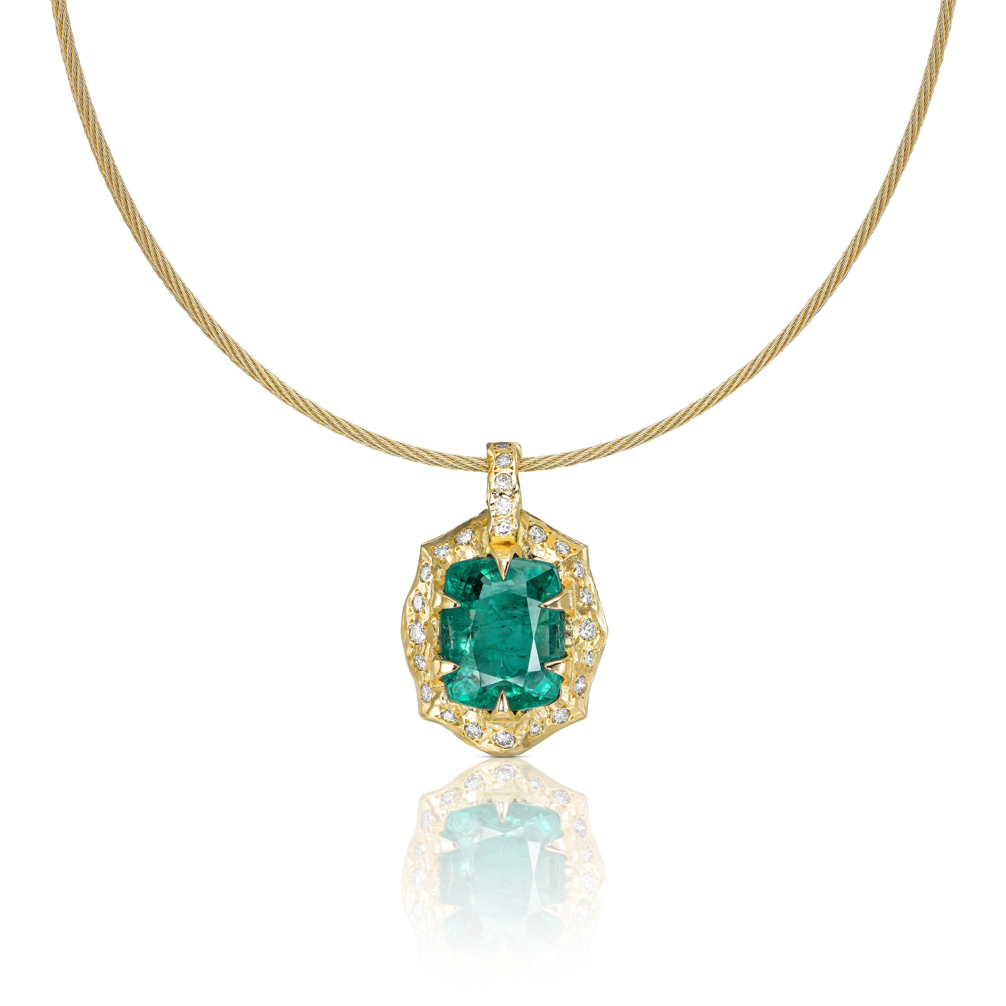 Close-up of 3.3 ct cushion-cut natural emerald surrounded by brilliant-cut diamonds in hand-carved 14K gold on a fine gold choker.