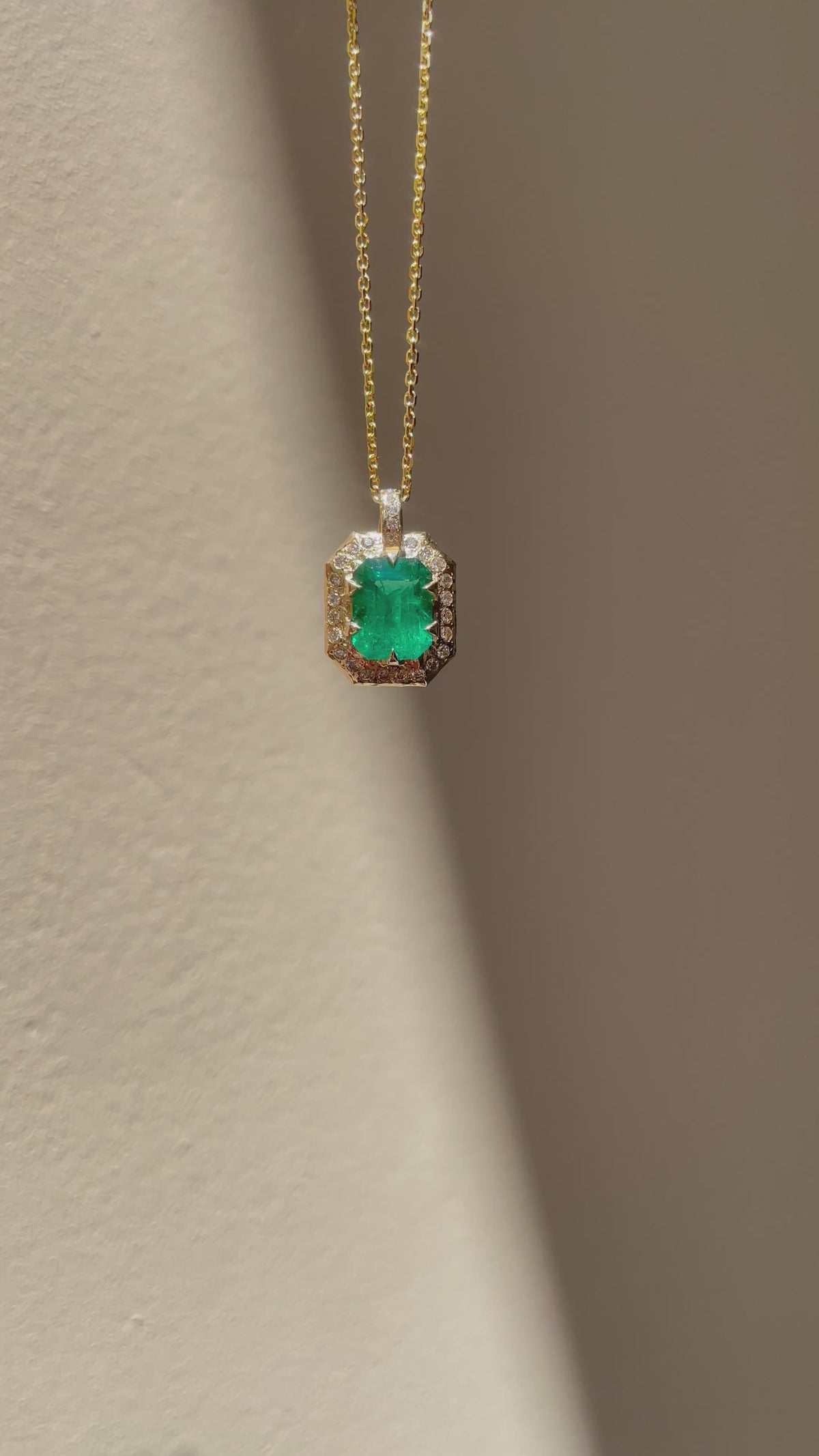 Emerald-cut natural emerald and diamond necklace in hand-carved 14K yellow gold, featuring a deep green center stone surrounded by natural diamonds.