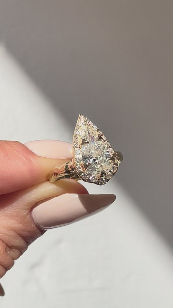 video of  2 CT pear-shaped natural diamond engagement ring with diamond halo and hand-carved organic gold band.
